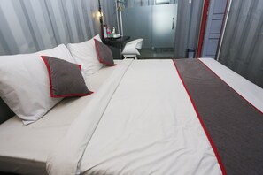 Une chambre d’hôtel moderne dotée d’un grand lit, d’un bureau et d’une douche en verre.