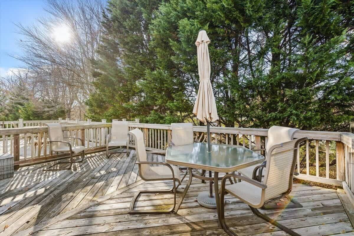 Eine Holzterrasse mit Gartenmöbeln, darunter ein Tisch und Stühle, sowie einem Sonnenschirm.