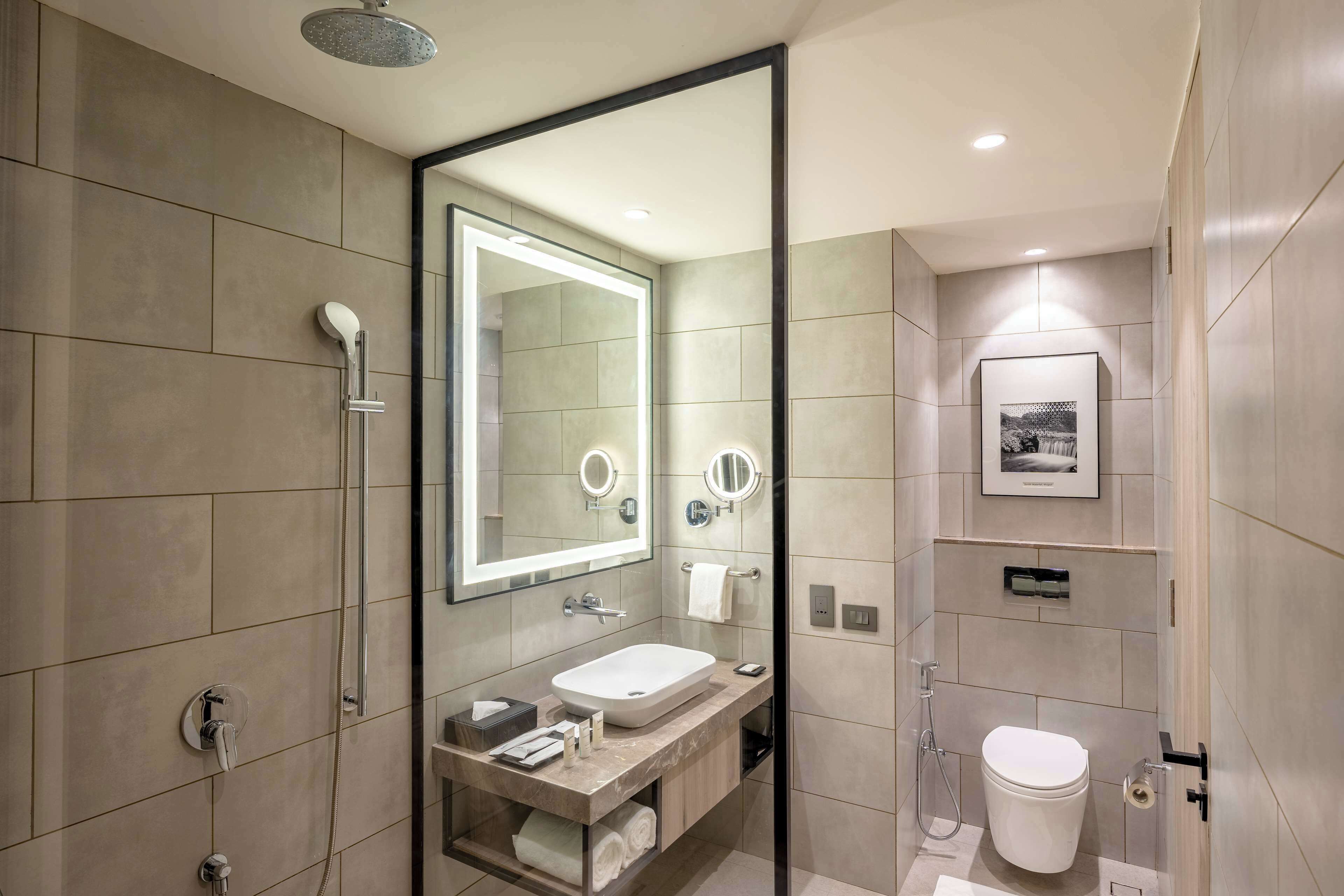 Ein modernes Badezimmer mit großem Spiegel, Waschbecken, Toilette und Dusche.