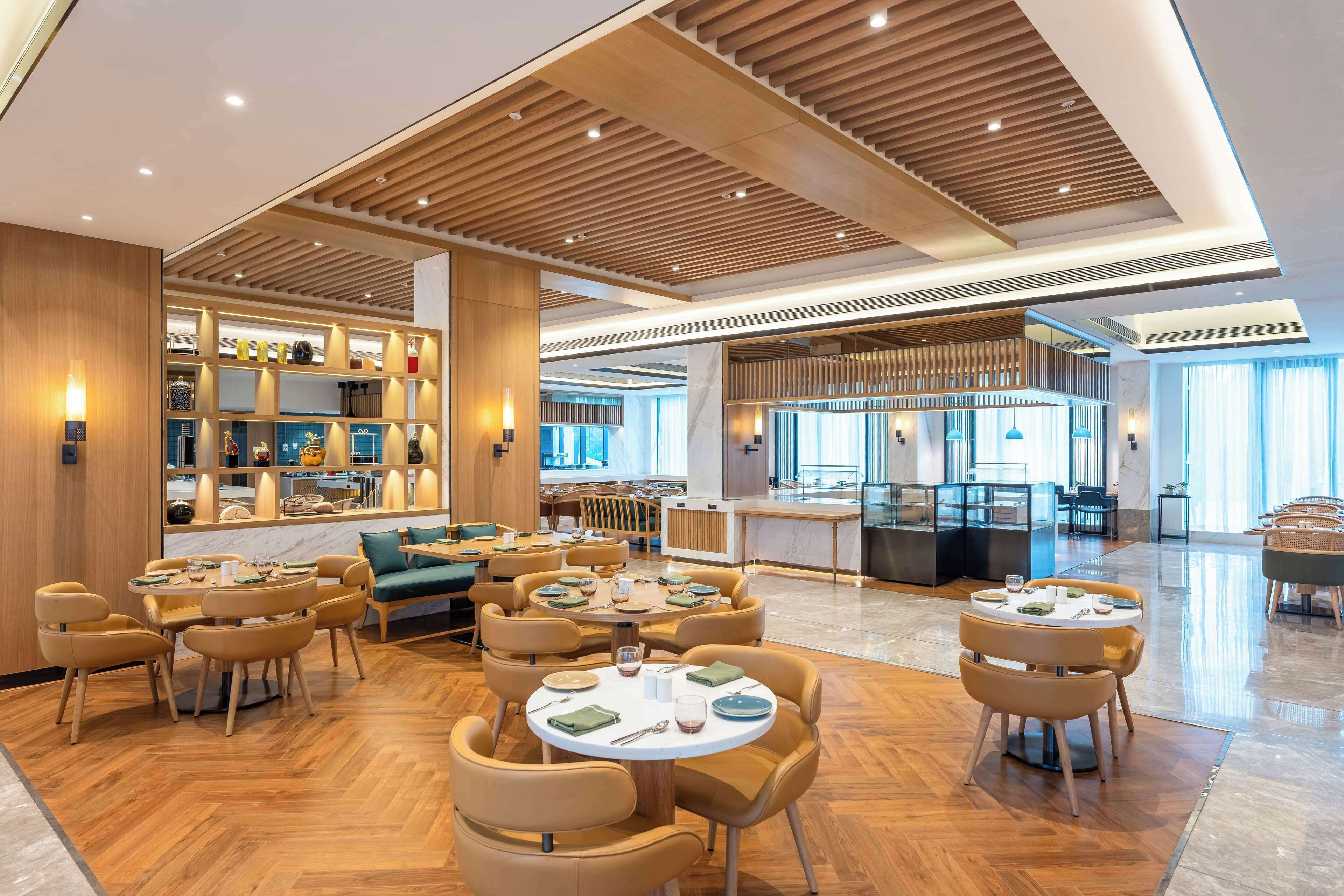 A spacious hotel lobby with multiple seating areas, a central bar, and a well-lit interior.
