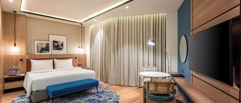 Una habitación de hotel moderna con cama, mesita de noche, lámpara y televisión.
