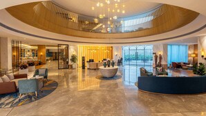 Un'ampia hall con una reception a forma di curva, zone relax e un soffitto alto caratterizzato da un originale design in legno.