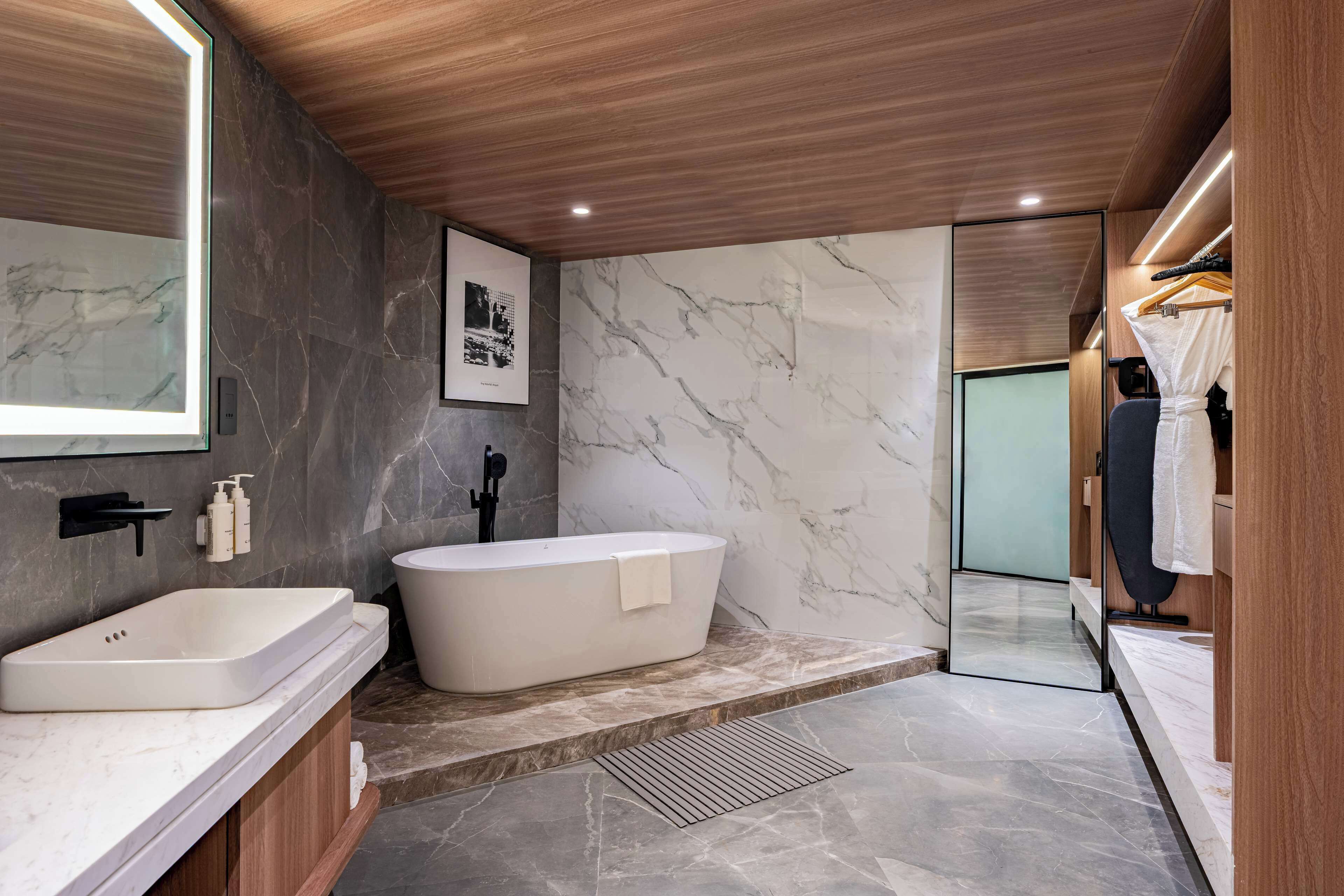 A modern bathroom with a freestanding bathtub, a vanity with a sink, and a large mirror.
