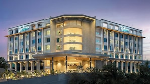 Un hotel moderno con facciata curva, numerosi balconi e un ingresso ben illuminato.