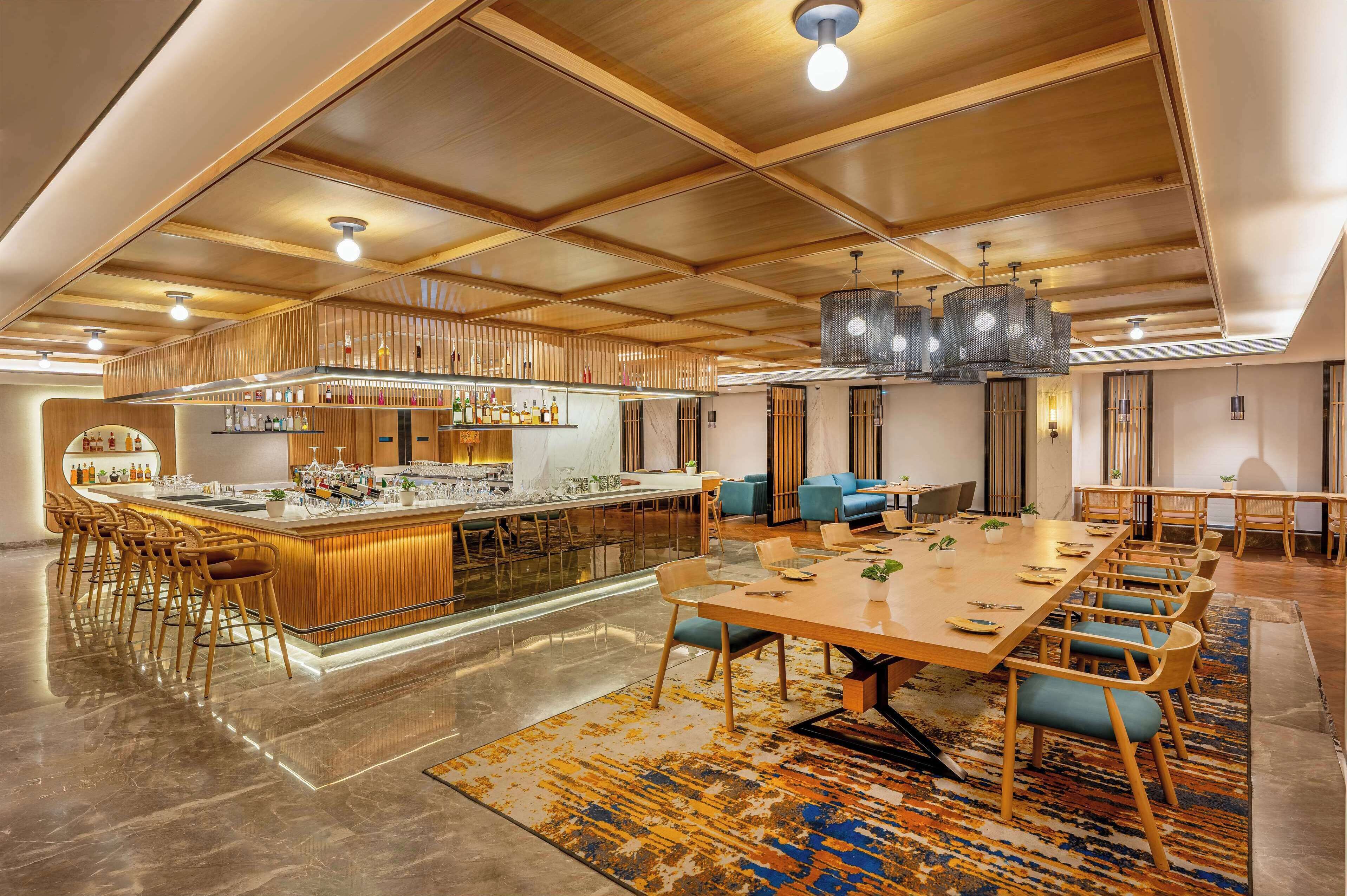Um amplo hall de hotel com área de bar central, espaços para sentar e design moderno.