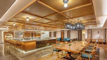 Um amplo hall de hotel com área de bar central, espaços para sentar e design moderno.
