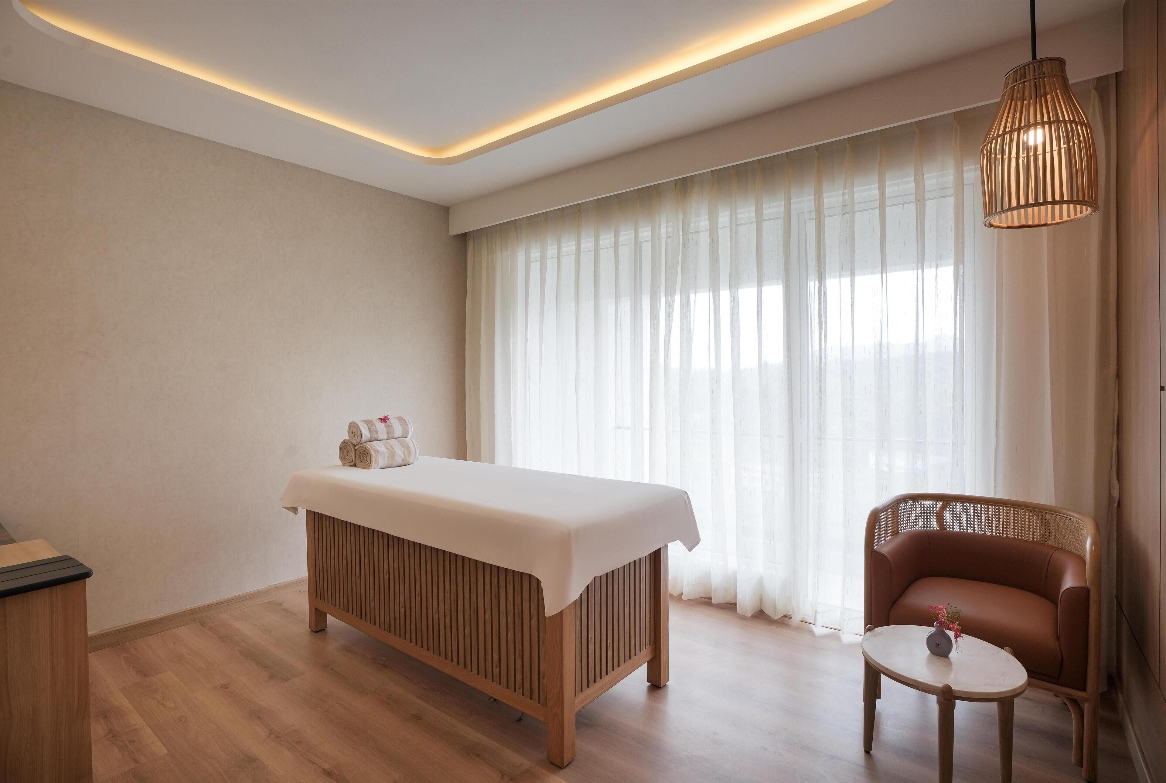 Ein Zimmer mit einem Holzbadezimmertisch, einem Korbstuhl und einem kleinen runden Tisch mit einer Vase.