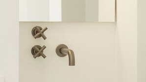 A bathroom with a white sink, a mirror above it, and two wall-mounted faucets. - FalcoMarino (Polignano a Mare)
