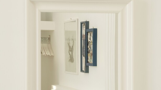 A room with a bed, a mirror, and wall-mounted artwork.