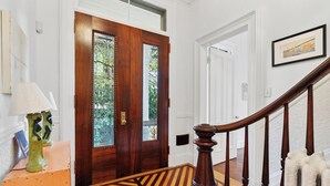 Eine Holztreppe mit Streifenmuster führt zu einer weißen Tür mit Glasscheiben.
