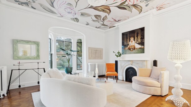 Ein geräumiges Wohnzimmer mit einem weißen Sofa, einem beigen Sessel und einem Kamin.