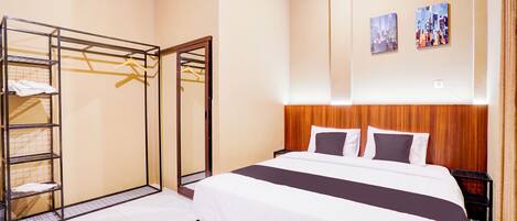 A hotel room with a bed, a wardrobe, and two wall-mounted artworks.