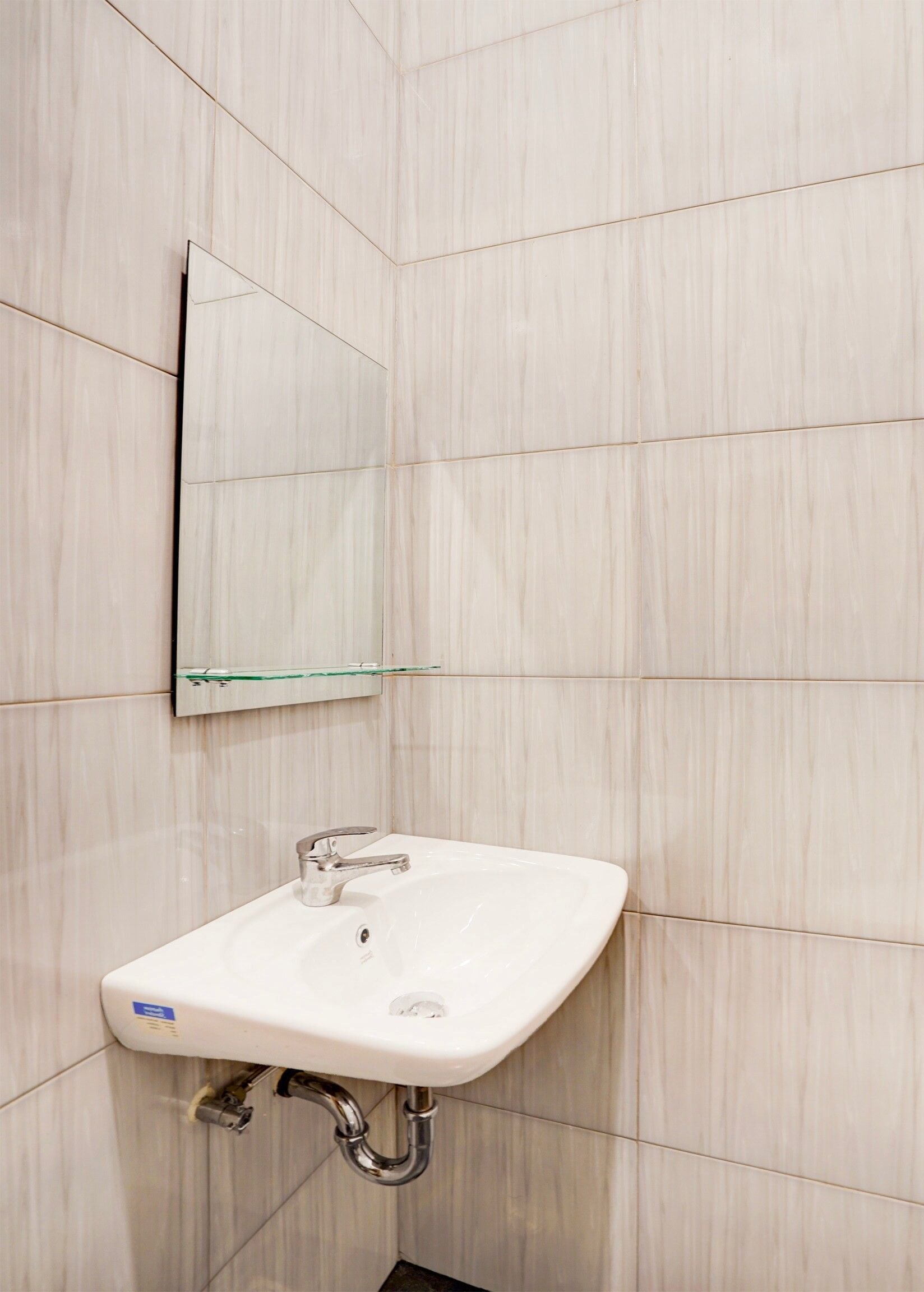 A bathroom with a white sink, a mirror, and tiled walls.