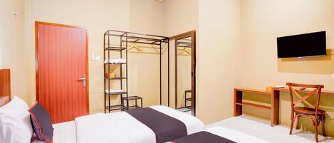 Quarto de hotel com duas camas, uma escrivaninha, uma cadeira, uma televisão e um guarda-roupa.