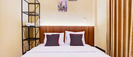 A hotel room with a bed, a metal shelf with towels, and two abstract paintings on the wall.