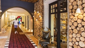 A hallway with a patterned carpet, a wooden log wall, and a black leather chair. - Ha(a)ïtza (La Teste-de-Buch)