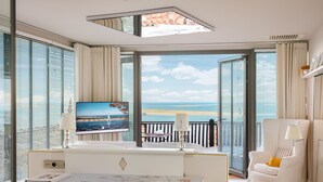A modern hotel room with a desk, chair, and a large TV screen displaying a scenic view. - La Co(o)rniche (La Teste-de-Buch)