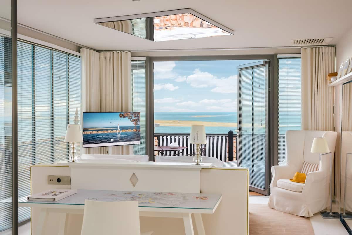 A modern hotel room with a desk, chair, and a large TV screen displaying a scenic view.