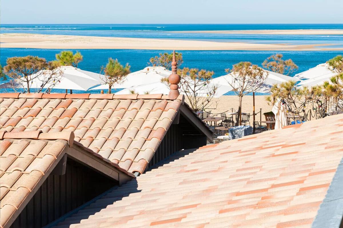 A rooftop terrace with a view of the beach and ocean.