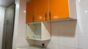 Un baño con azulejos blancos, un gabinete naranja sobre el lavabo y un espejo.