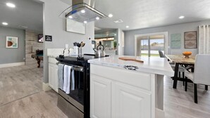 A modern kitchen with a central island, built-in oven, and a dining area with a table and chairs. - Luxury Vegas Getaway Pickleball, Pool & Game Room! (Las Vegas)