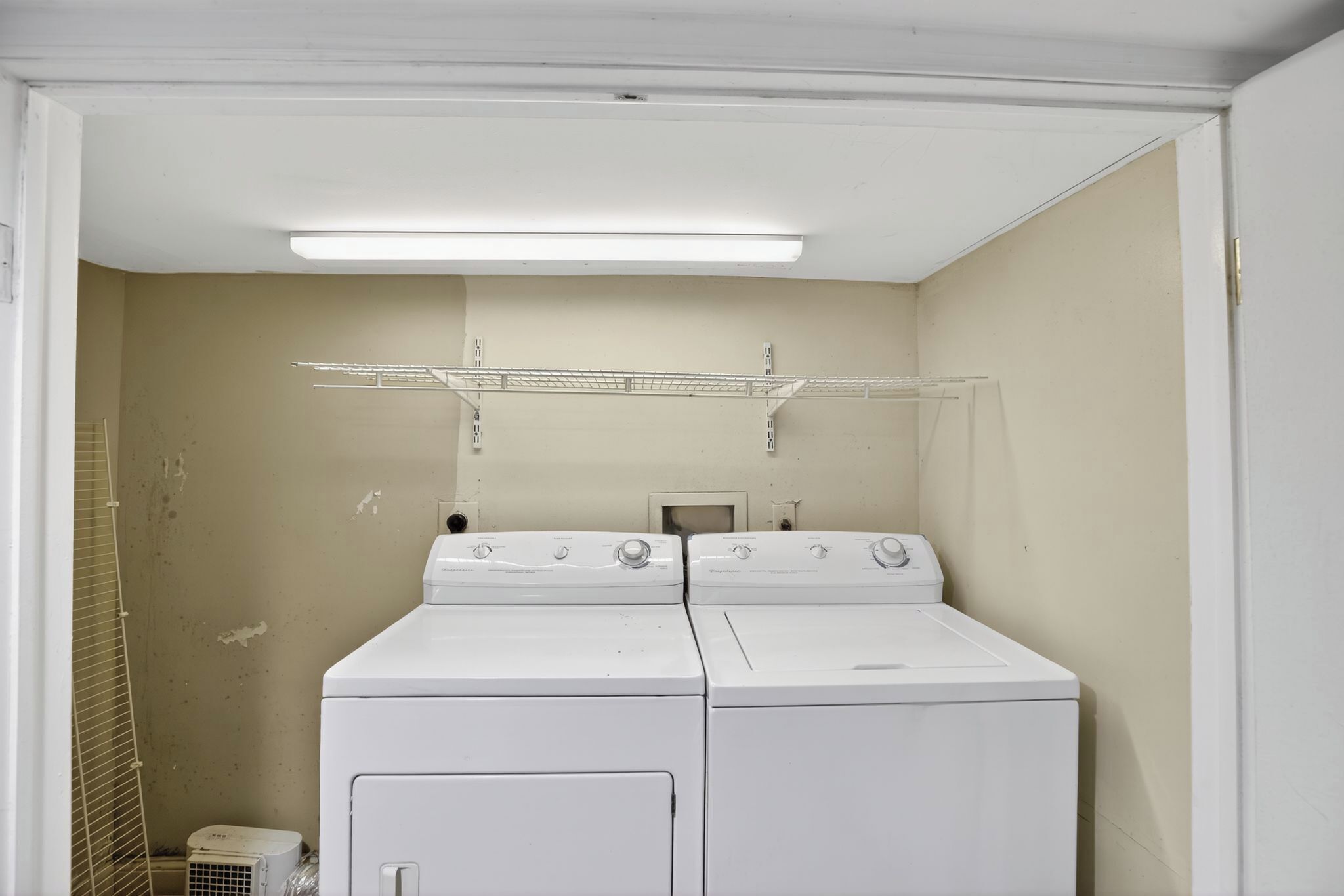 Une buanderie équipée de deux machines à laver et deux sèche-linge superposés, d’un étendoir métallique et d’un petit radiateur.
