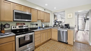 A kitchen with wooden cabinets, stainless steel appliances, and a tiled floor. - Hudson house (Baltimore)