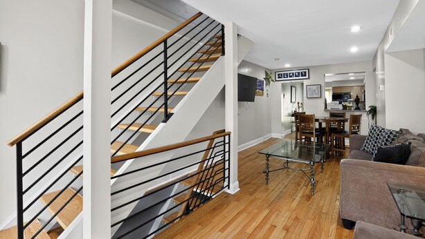 A modern living room with a staircase, a dining area, and a kitchen in the background. - Hudson house (Baltimore)