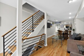 A modern living room with a staircase, a dining area, and a kitchen in the background. - Hudson house (Baltimore)