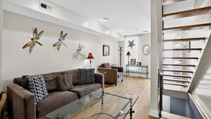 A modern living room with a brown sofa, glass coffee table, and decorative wall art. - Hudson house (Baltimore)