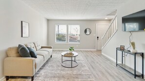A living room with a beige sofa, a round coffee table, and a staircase leading to another level.