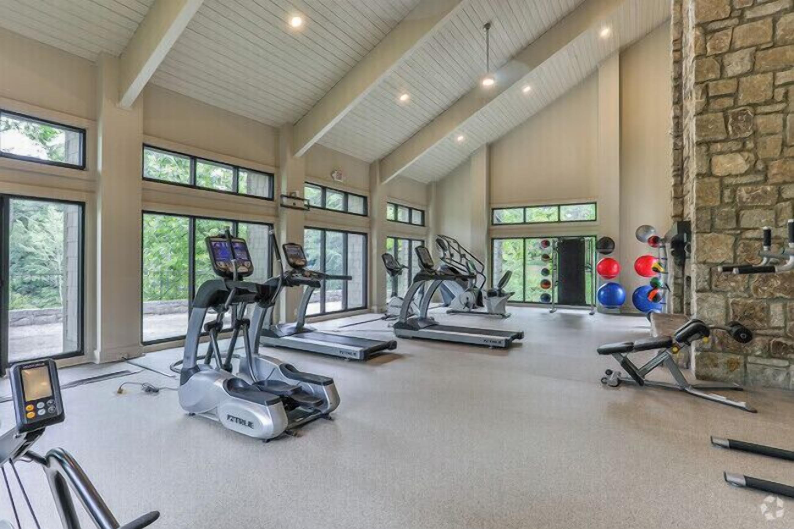 A spacious gym with treadmills, elliptical machines, and free weights.