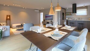 A modern living room with a dining area, a kitchen, and a TV in the background. - Holiday House with Pool Casa Lavanda (Bale)