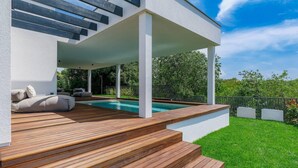 A modern outdoor pool area with wooden decking and a covered seating area. - Holiday House with Pool Casa Lavanda (Bale)