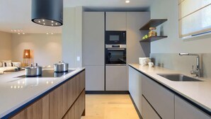 A modern kitchen with a central island, built-in oven, and a large window providing natural light. - Holiday House with Pool Casa Lavanda (Bale)