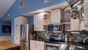 A modern kitchen with stainless steel appliances, white cabinets, and a black marble countertop. - Back Alley Apartment, walk Downtown and Duke. (Durham)