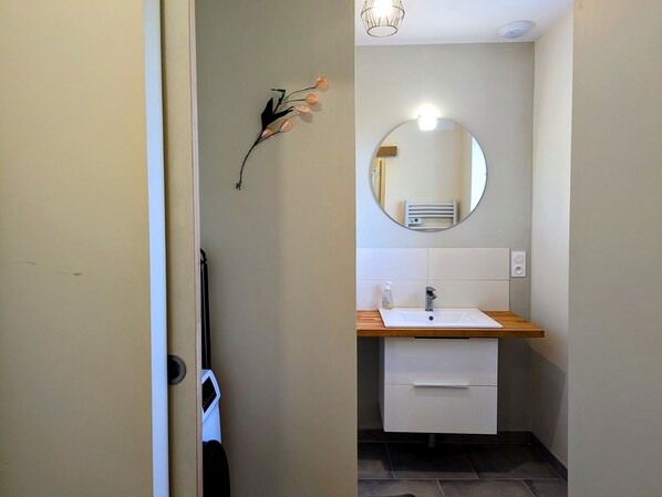 A compact bathroom with a white sink, a mirror, and a towel rack.