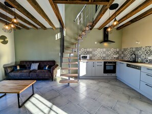 A modern kitchen with a built-in microwave, a wooden staircase, and a dining area with a bench. - Quiet house near Valençay, close to Beauval Zoo (Valençay)