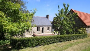 Ein Steinhaus mit rotem Dach, Schornstein und einer kleinen Veranda.