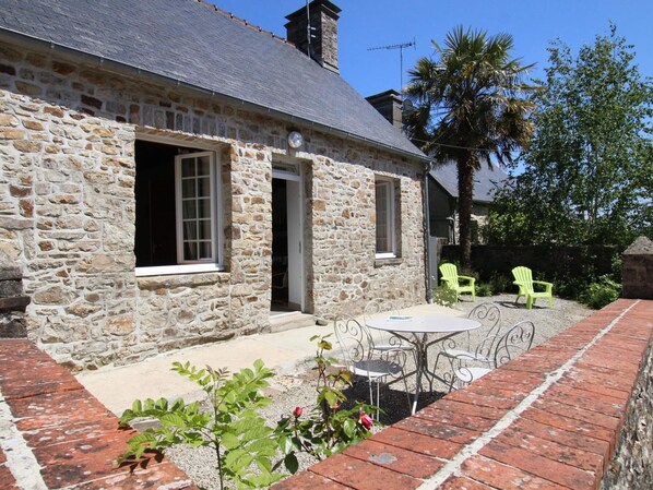 Charming cottage with a traditional stone exterior, patio, and lush greenery.