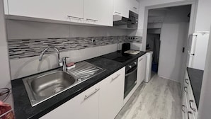 A modern kitchen with white cabinets, a black countertop, and a tiled backsplash.
