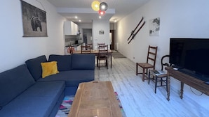 A modern living room with a sofa, coffee table, TV, and dining area with chairs and a table.