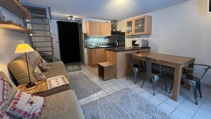 A compact living space with a kitchenette, a dining area, and a sofa with a lamp.