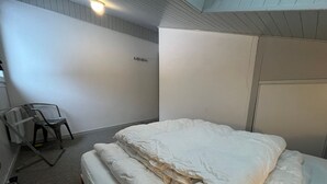 A bedroom with a bed, a chair, and a wardrobe.