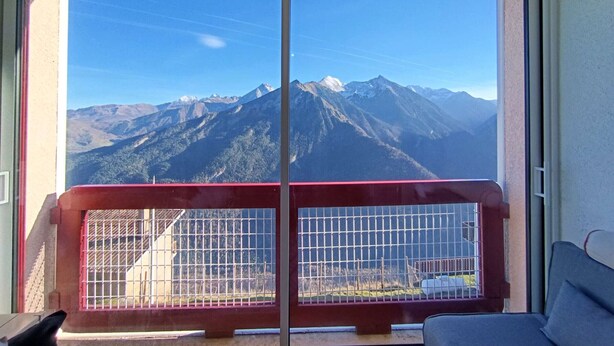 Une pièce dotée d’une grande porte-fenêtre coulissante donnant sur un balcon avec vue sur les montagnes.