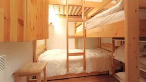 Une chambre avec un lit superposé en bois, une échelle et un petit tabouret.
