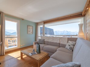 Ein Wohnzimmer mit einer Couch, einem Couchtisch und Bergblick durch große Fenster.