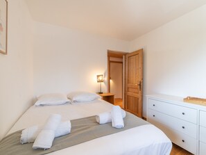 Ein Hotelzimmer mit einem Bett, einem Nachttisch mit Lampe, einer Holztür und einer weißen Kommode.
