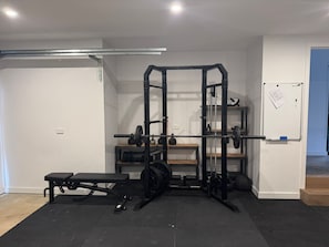 A compact home gym with a squat rack, bench, and weight plates.