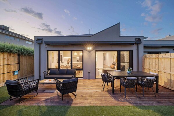 A modern outdoor patio with a dining table, chairs, and a sofa.